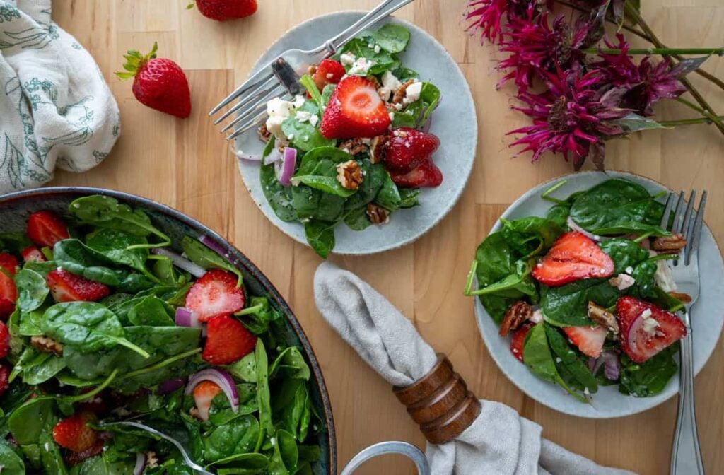 Strawberry Spinach Salad with Poppyseed Vinaigrette on small plates next to large salad bowl