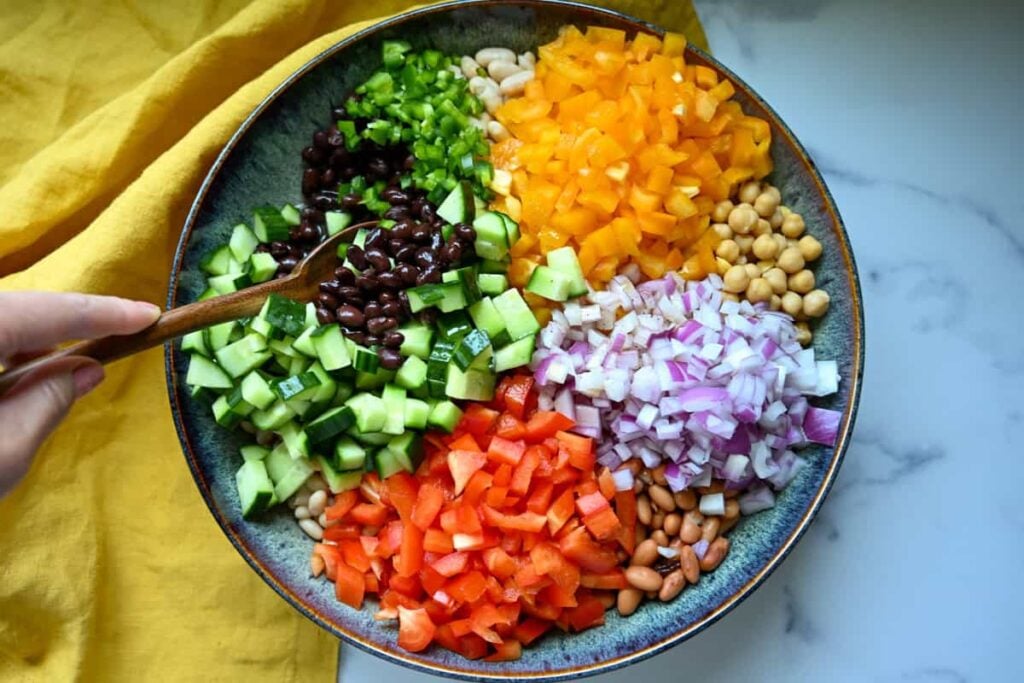 mixing cowboy caviar in a large bowl with a wooden spoon
