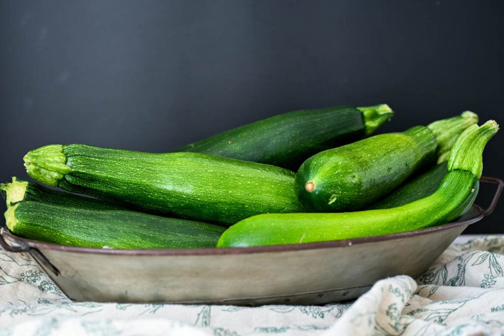 a metal bowl with zucchini piled in it