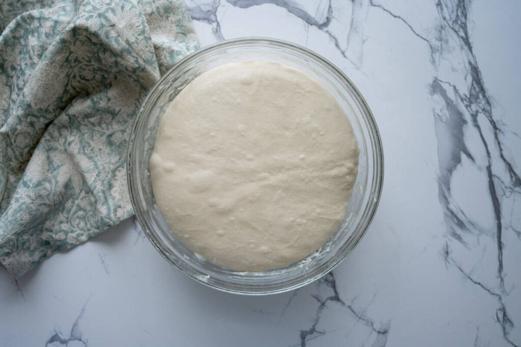 sourdough ciabatta dough in a glass bowl after bulk fermentation