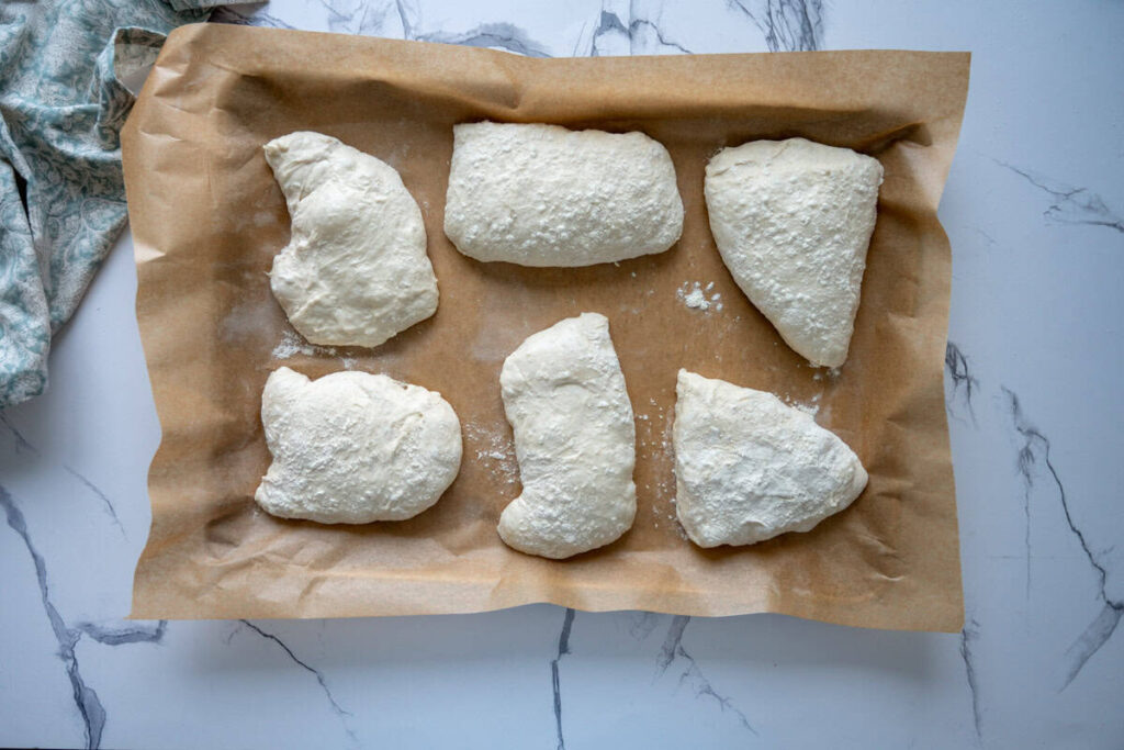 divided sourdough ciabatta dough on a parchment lined baking sheet