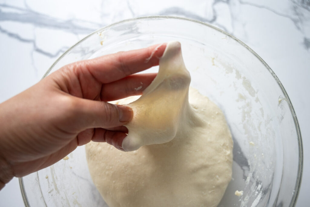 stretching sourdough ciabatta bread to show it passes the window pane test