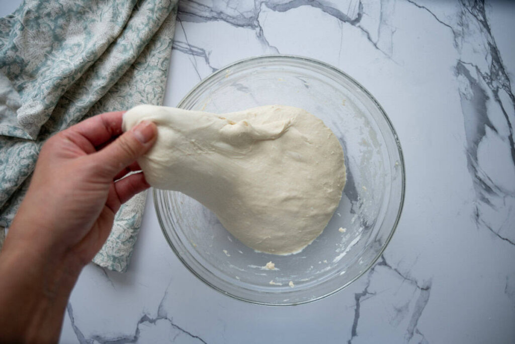 stretching sourdough ciabatta dough in a glass bowl