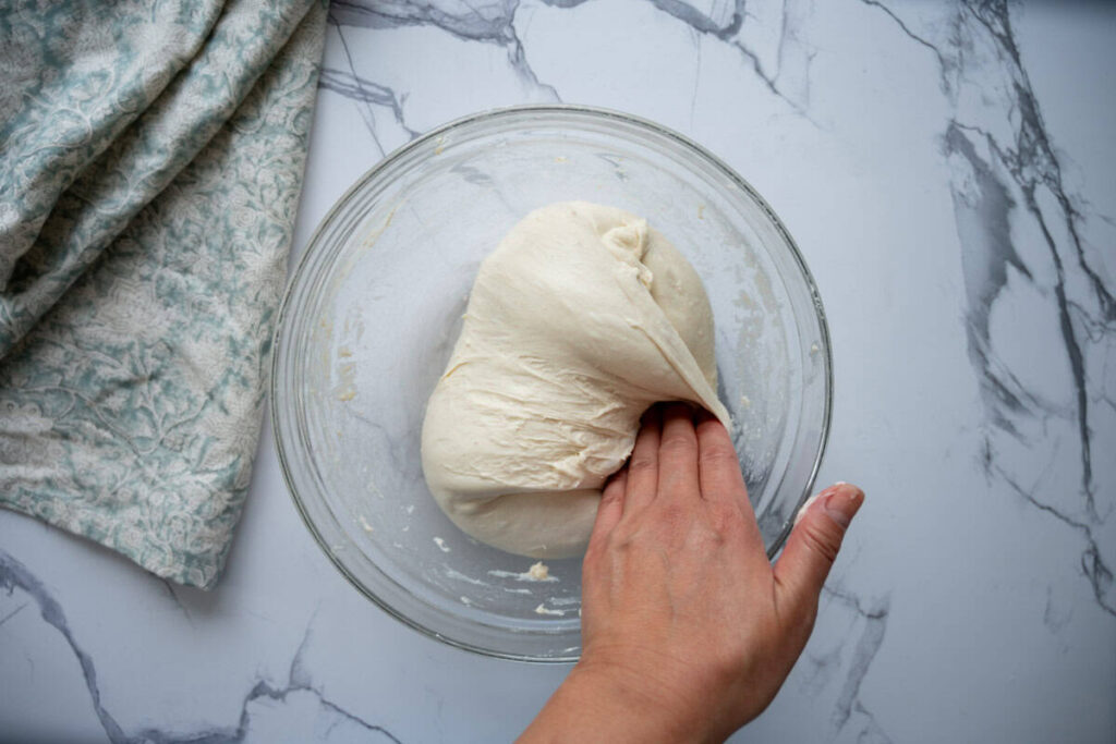 folding sourdough ciabatta dough in a glass bowl