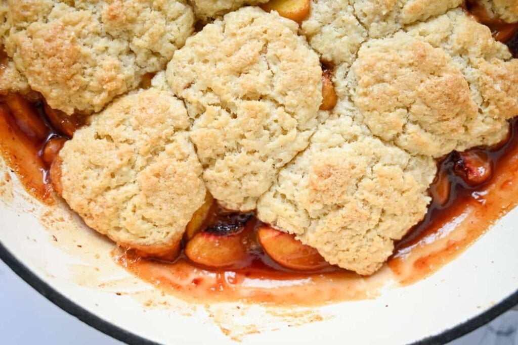 baked sourdough peach cobbler in a braiser