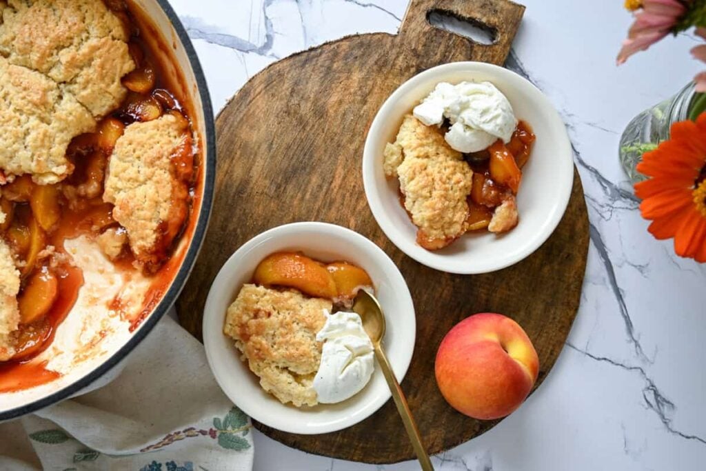 sourdough peach cobbler in small bowls on a wood platter