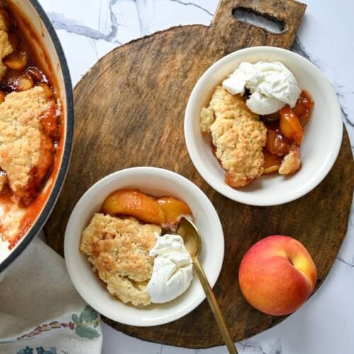 sourdough peach cobbler in small bowls on a wood platter