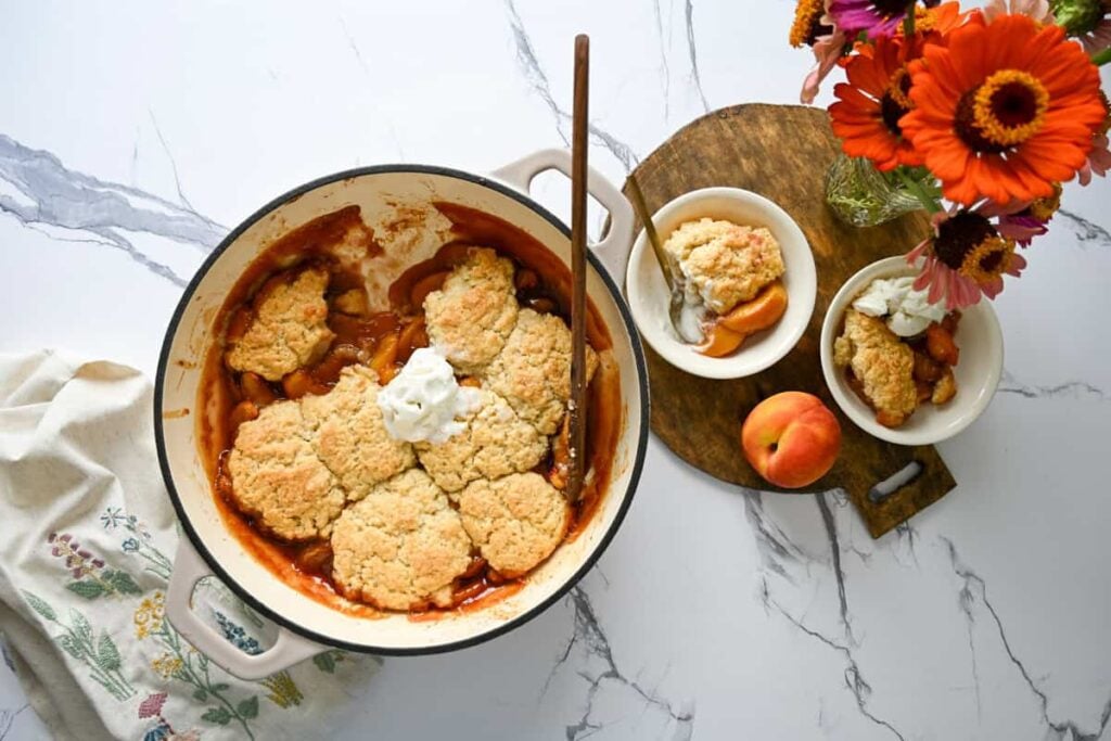 sourdough peach cobbler with two bowls and flowers