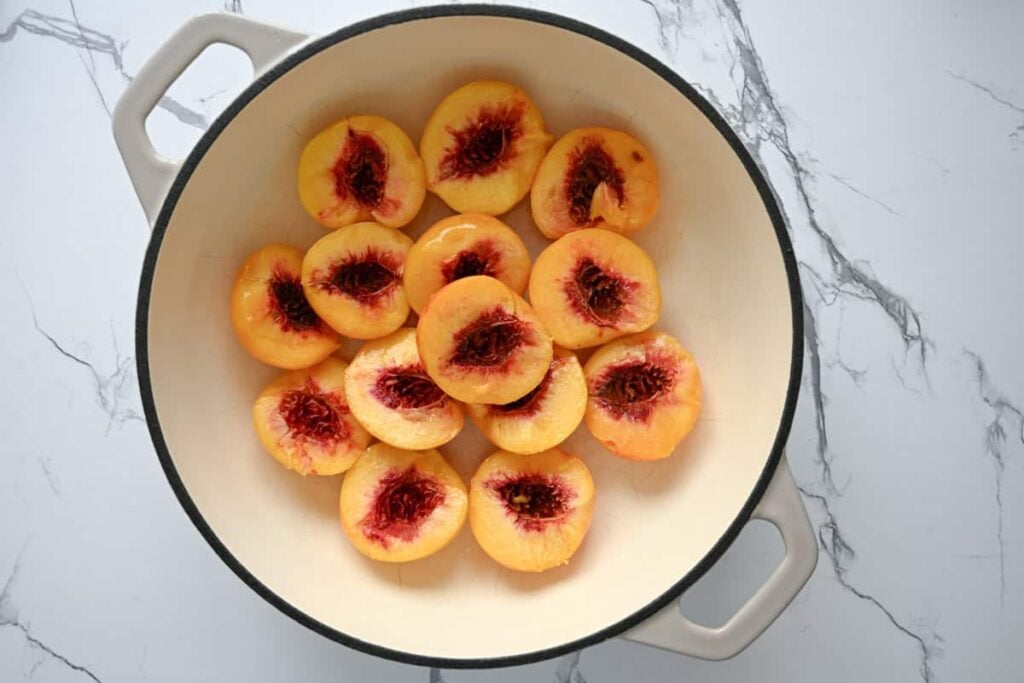 halved peaches in a shallow braiser