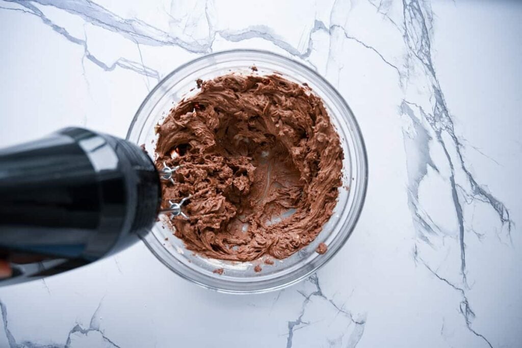 mixing chocolate frosting in a glass bowl