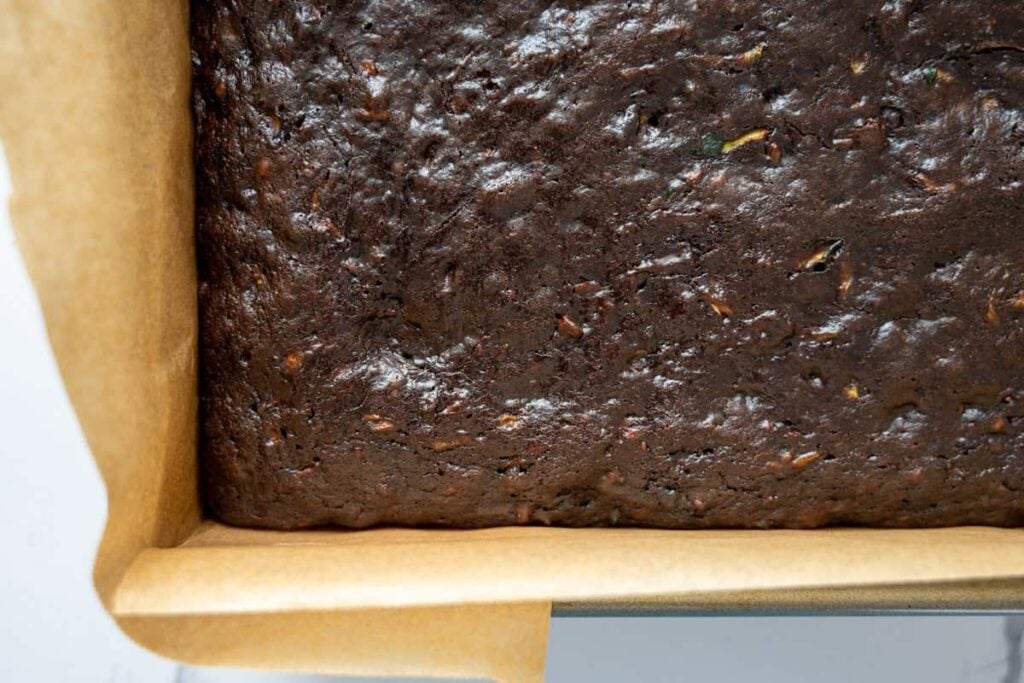 baked chocolate sourdough zucchini cake in a parchment lined baking pan
