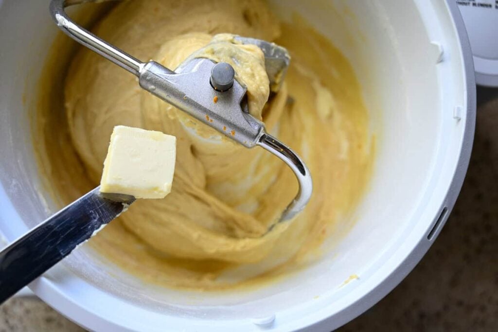 adding a pat of butter to panettone dough in a stand mixer