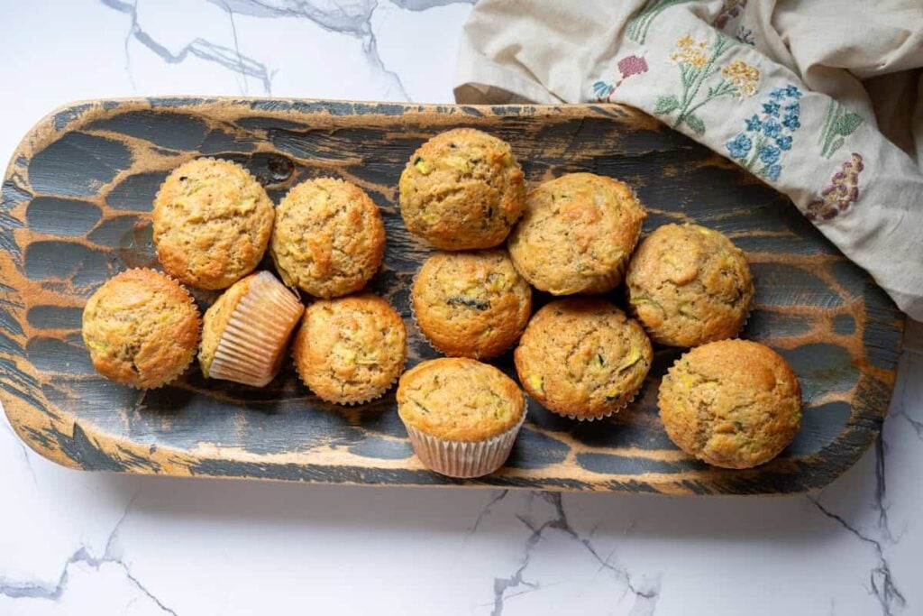 sourdough zucchini muffins in a wooden bowl with a linen cloth