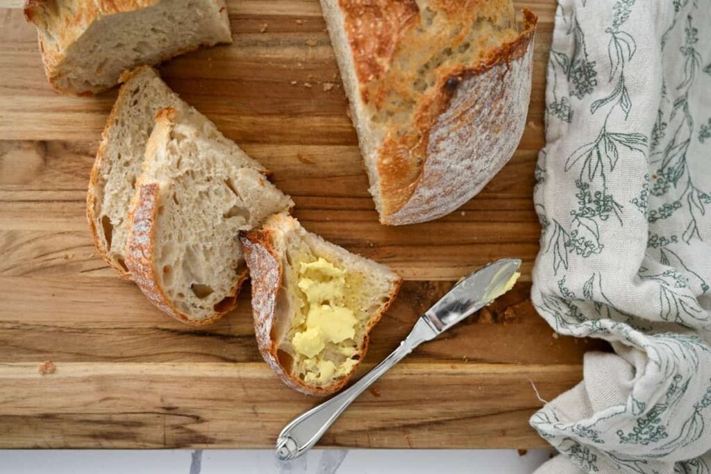 same day sourdough bread slices on a wooden board with a bit of butter on one piece