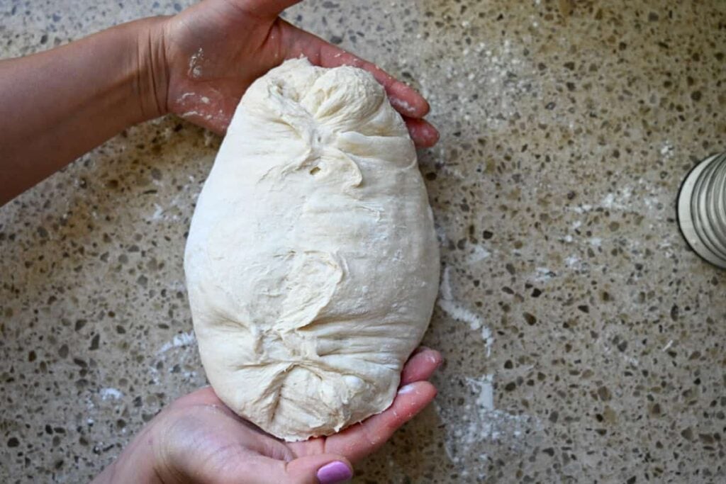 hands under two sides of sourdough bread