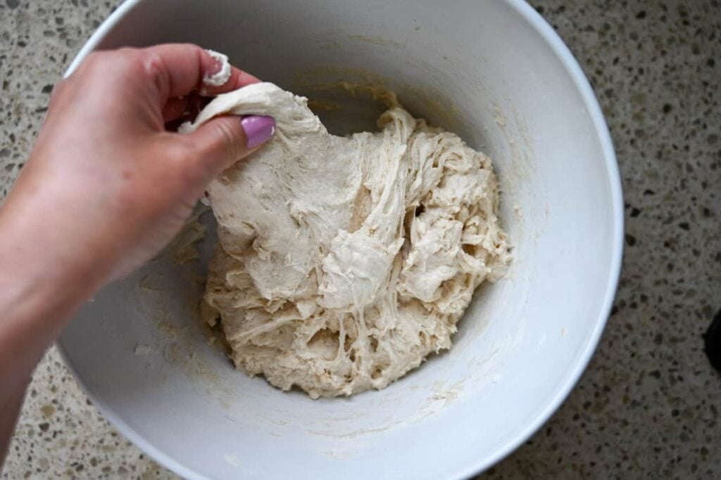 stretching sourdough in a white bowl