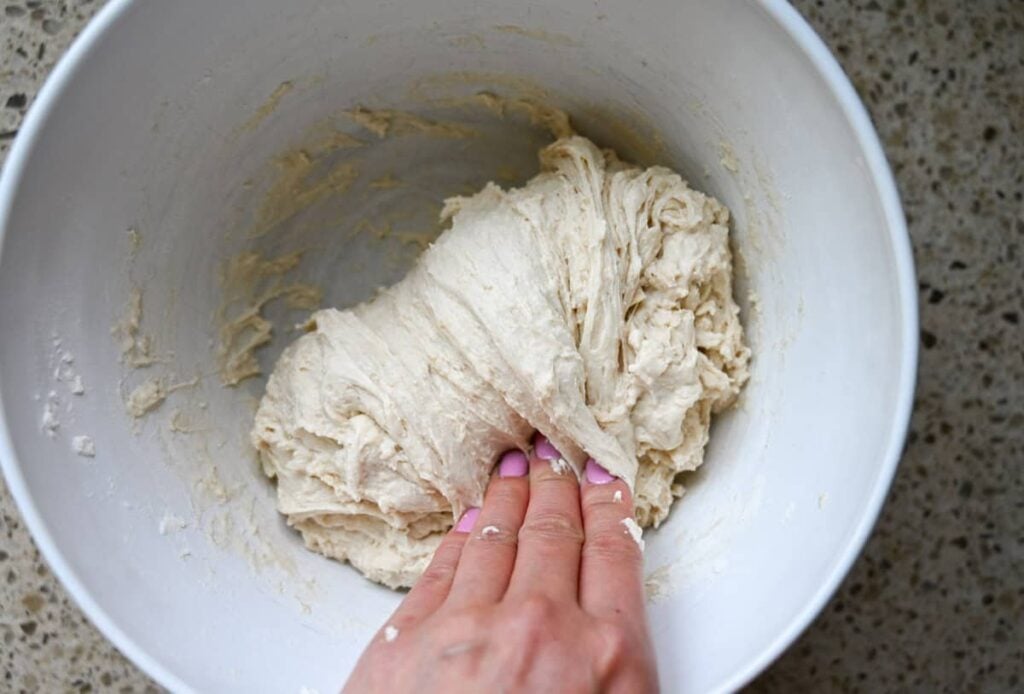 folding sourdough in a white bowl