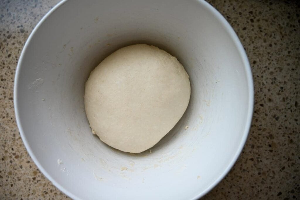 bulk fermenting same day sourdough bread dough in a white bowl