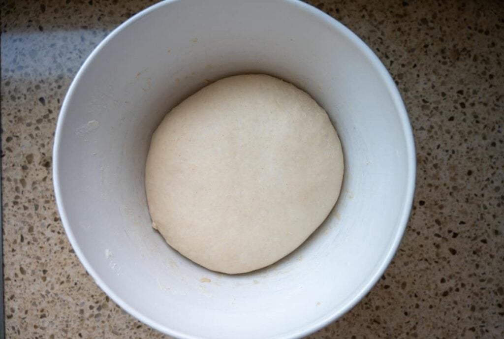 bulk fermenting same day sourdough bread dough in a white bowl