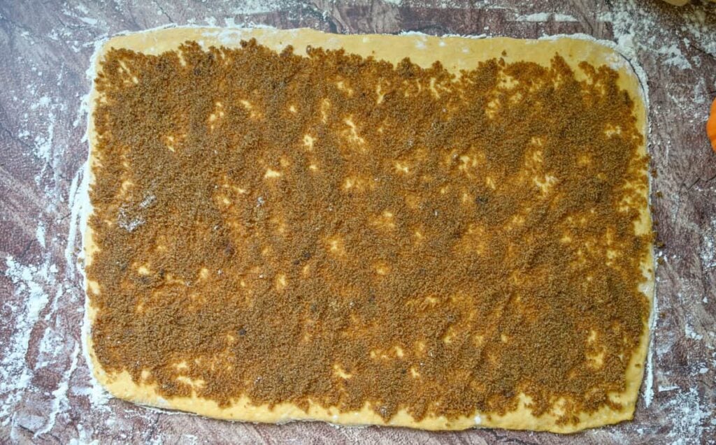 rolled out sourdough pumpkin cinnamon rolls dough with pumpkin spice filling