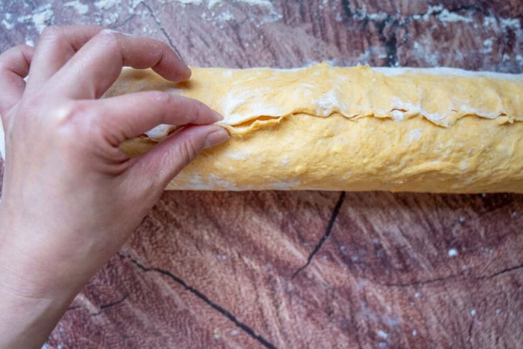 pinching the seam of sourdough pumpkin cinnamon rolls dough