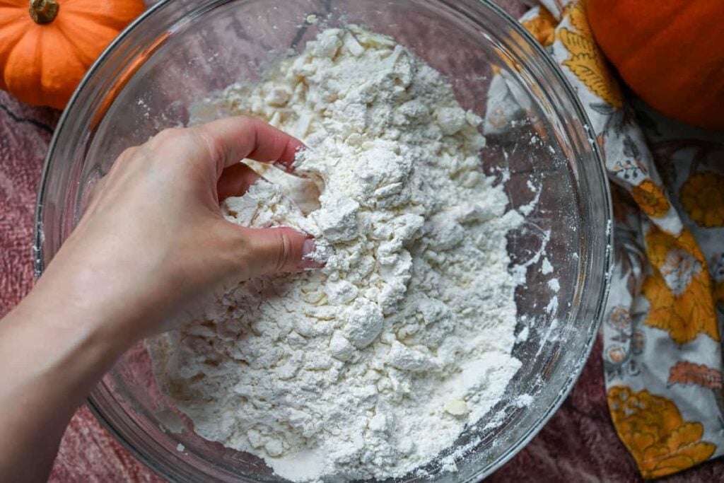 mixing butter into dry ingredients by hand in a glass bowl