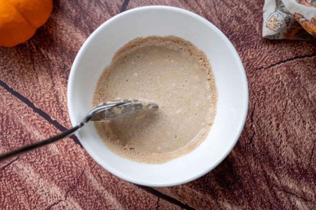 mixing yeast and water in a small white bowl with a spoon